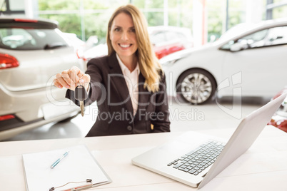 Smiling saleswoman holding car key Smiling saleswoman holding car key