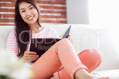 Smiling asian woman on couch reading