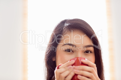 Asian woman relaxing on couch with coffee