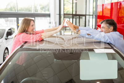 Casual smiling couple hugging their new car Casual smiling couple hugging their new car
