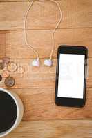 Coffee and black smartphone with white headphones