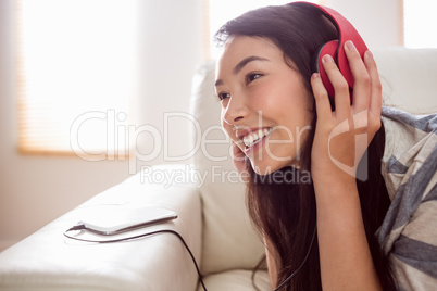 Smiling asian woman on couch listening to music