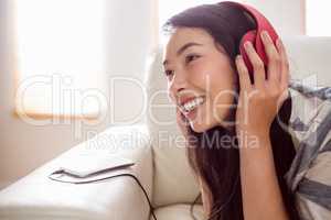 Smiling asian woman on couch listening to music