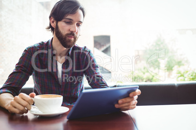 Hipster student using tablet in canteen