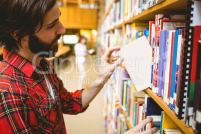 Hipster student picking a book in library