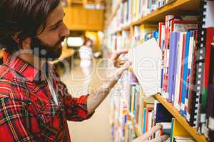 Hipster student picking a book in library