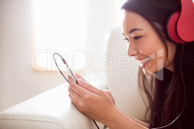 Smiling asian woman on couch listening to music