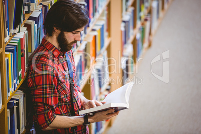 Student reading a book from shelf in library