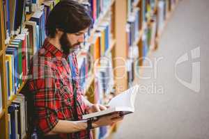 Student reading a book from shelf in library