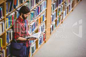 Student reading a book from shelf in library