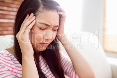 Asian woman getting headache on couch