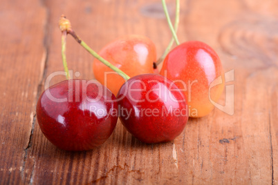 wooden plate with dark red juicy cherries close up