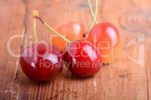 wooden plate with dark red juicy cherries close up