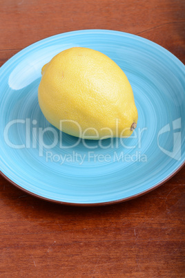 Whole lemon on a blue plate on wooden background