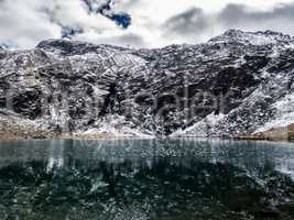 spiegelnder See vor Berg mit Eis und Schnee