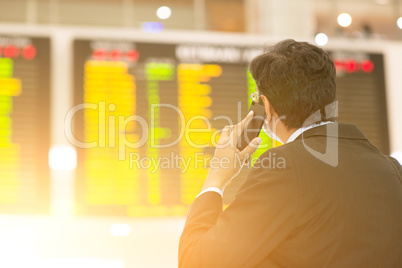 Businessman looking at airport flight timetable