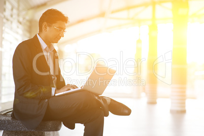 Indian businessman using laptop computer at railway station.