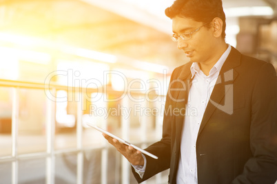 Indian Businessman using tablet computer at train station