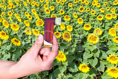 Hand holding asthma inhaler in front of the field