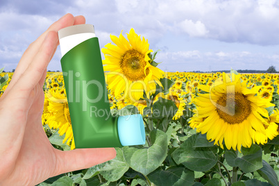 Hand holding asthma inhaler in front of the field