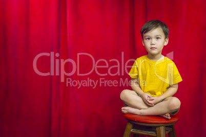Mixed Race Boy Sitting on Stool in Front of Curtain