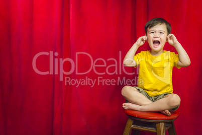 Boy, Fingers In Ears on Stool in Front of Curtain