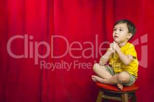 Mixed Race Boy Sitting on Stool in Front of Curtain