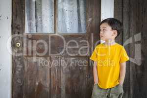 Melancholy Mixed Race Boy Standing In Front of Door