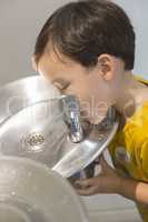 Mixed Race Boy Drinking From the Water Fountain