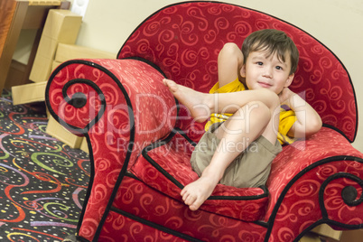Mixed Race Boy Relaxing in Comfortable Red Arm-Chair