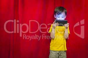 Mixed Race Boy Watching Cell Phone in Front of Curtain