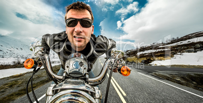 Funny Biker in sunglasses and leather jacket racing on mountain