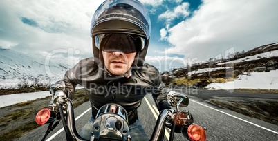 Biker in helmet and leather jacket racing on mountain serpentine