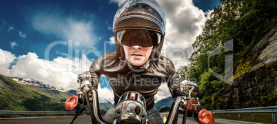 Biker in helmet and leather jacket racing on mountain serpentine