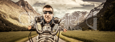 Funny Biker in sunglasses and leather jacket racing on mountain