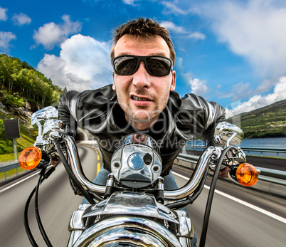 Funny Biker in sunglasses and leather jacket racing on mountain