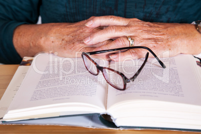Hands of an elderly woman lying on the book