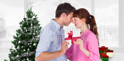 Composite image of loving couple holding a gift
