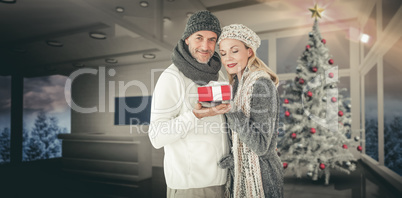 Composite image of happy winter couple with gift