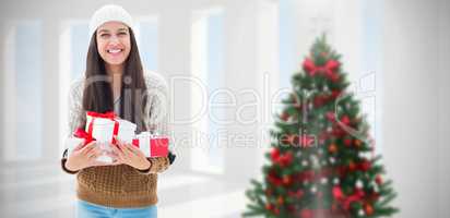 Composite image of festive brunette holding gifts