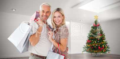 Composite image of happy couple with shopping bags and credit ca