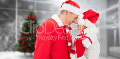 Composite image of festive mature couple holding gift