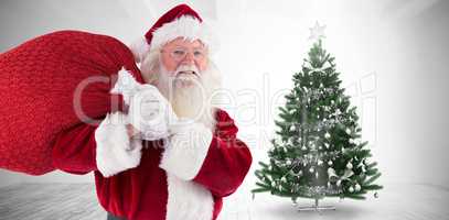 Composite image of santa carries his red bag and smiles