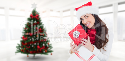 Composite image of smiling brunette holding christmas gifts