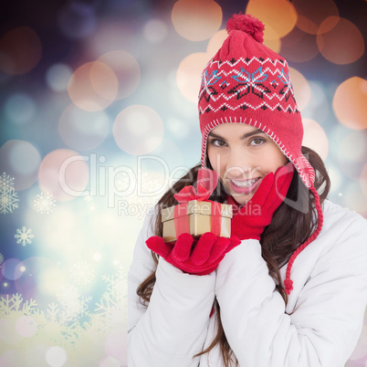 Composite image of surprised brunette in winter clothes holding