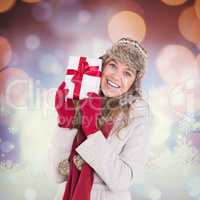 Composite image of happy blonde in winter clothes holding gift