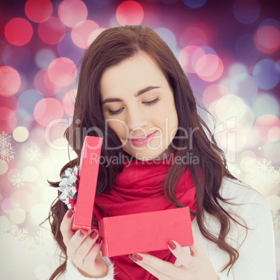 Composite image of pretty brunette opening christmas gift