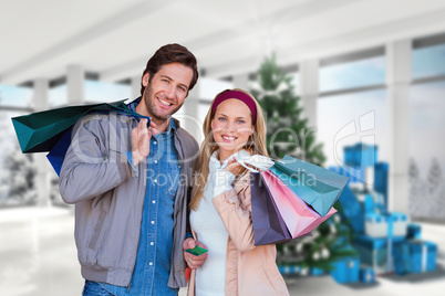 Composite image of smiling couple with shopping bags in front of