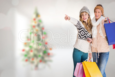 Composite image of beautiful women holding shopping bags pointin