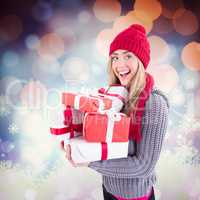 Composite image of festive blonde holding pile of gifts